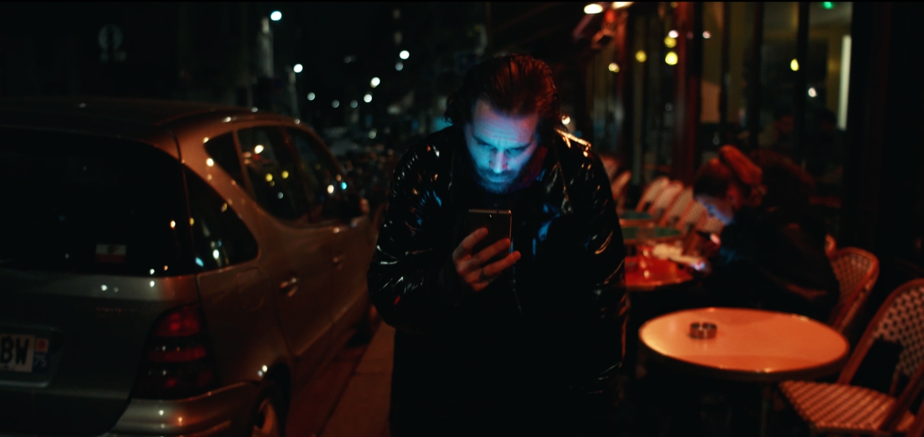 Personnage du Premier moi consultant son téléphone dans une rue de nuit